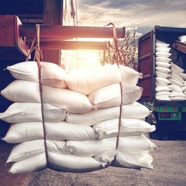 Forklift handling white sugar bags from warehouse for stuffing into container truck for export, vintage tone.
